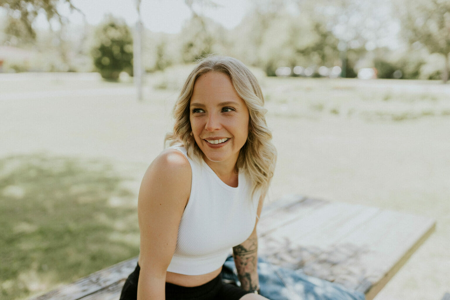 Marie-Ève Lestage souriante sur une table de picnic - Shooting photo Virtuelle & Co été 2022